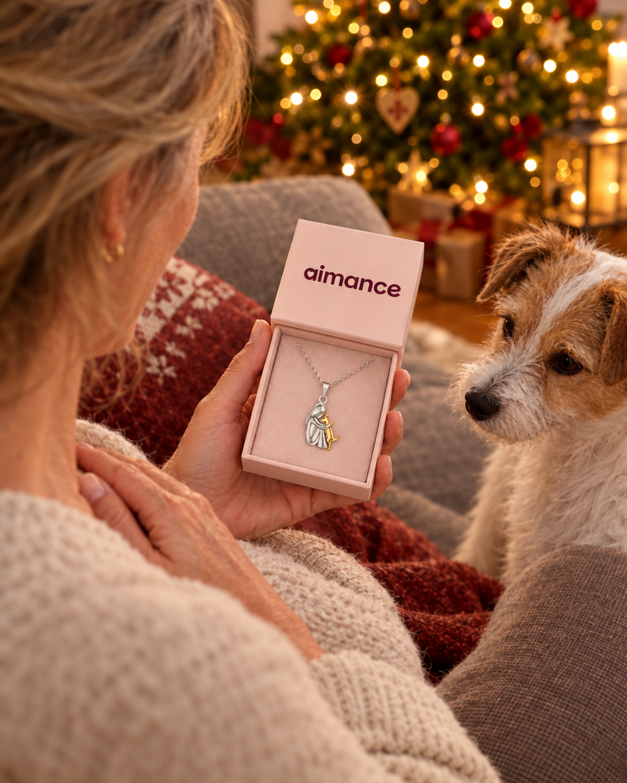 Une femme ouvre un écrin Aimance près du sapin, son chien à côté d'elle